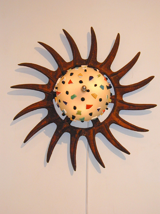 A sconce creacted from broken Fiesta, glass and a harrow